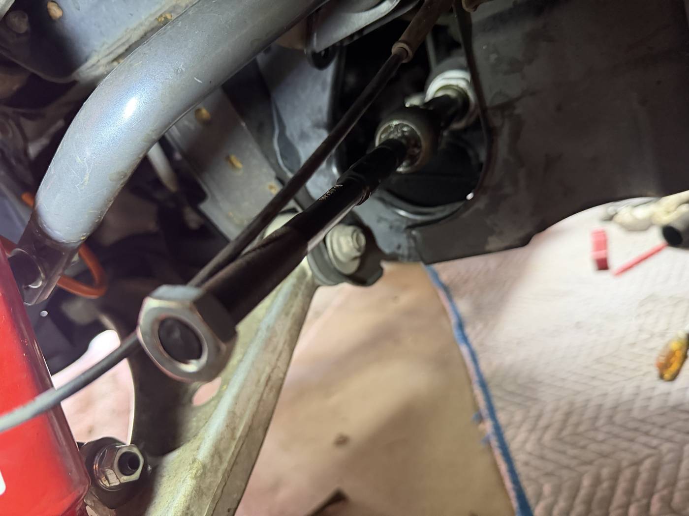 Close-up of a cowl mounting screw sealed with a heavy application of black sealant on the Miata's windshield cowl